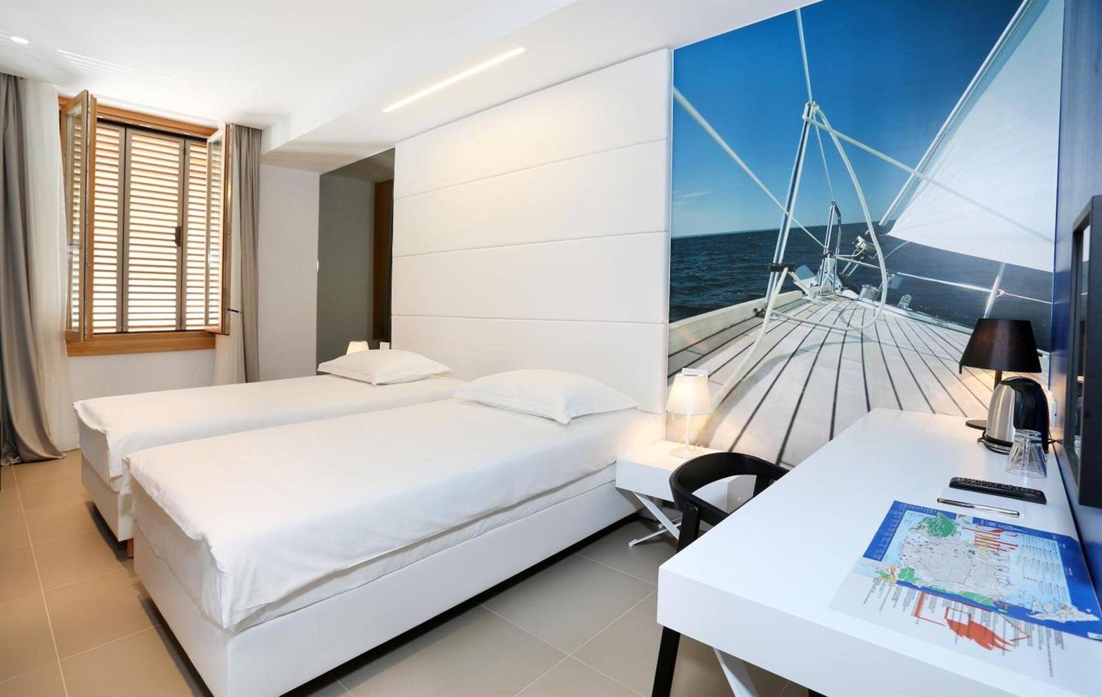 Twin room with a desk and a large sailing photo mural on the wall