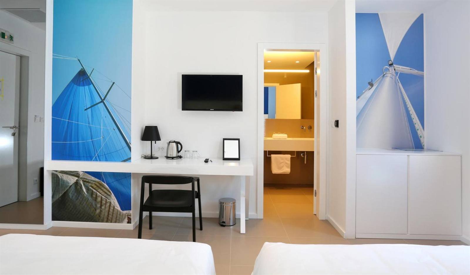 Room with a desk, wall-mounted TV, kettle and the bathroom entrance