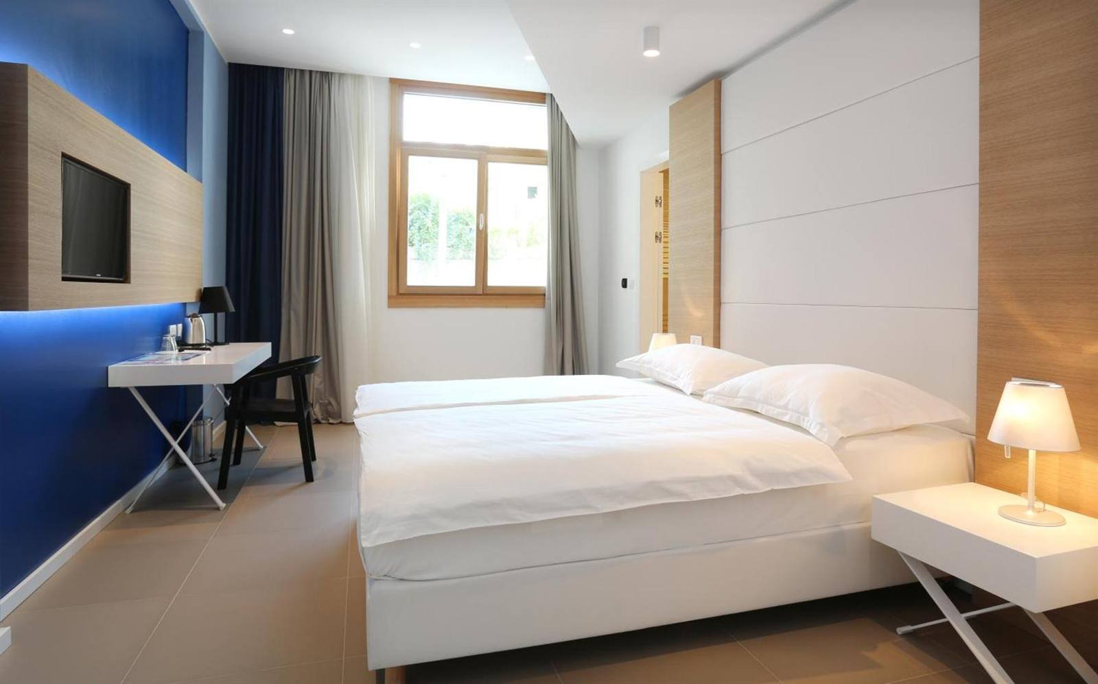 Deluxe double room with a window, desk and a blue accent wall